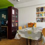 Moderner Raum mit Tisch und Stühlen auf Holzboden Leuchtend grüne Decke Regale mit Comics an der Wand und ein Computerarbeitsplatz bieten eine kreative Atmosphäre Moderner Raum mit Tisch und Stühlen auf Holzboden Leuchtend grüne Decke Regale mit Comics an der Wand und ein Computerarbeitsplatz bieten eine kreative Atmosphäre